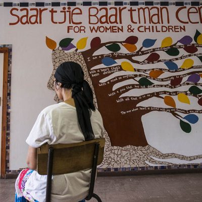 December 2 2015 - The Women’s Centre: Kamiela sits at the entrance to the Women’s Centre in front of her favourite mural. The Saartjie Baartman Centre for Women and Children, based in Klipfontein Road in Manenberg, is a one-stop centre for women & children who are survivors of abuse; Kamiela has been living at the safe haven for six months partcipating in the kitchen program as part of her ongoing care. Picture by David Harrison